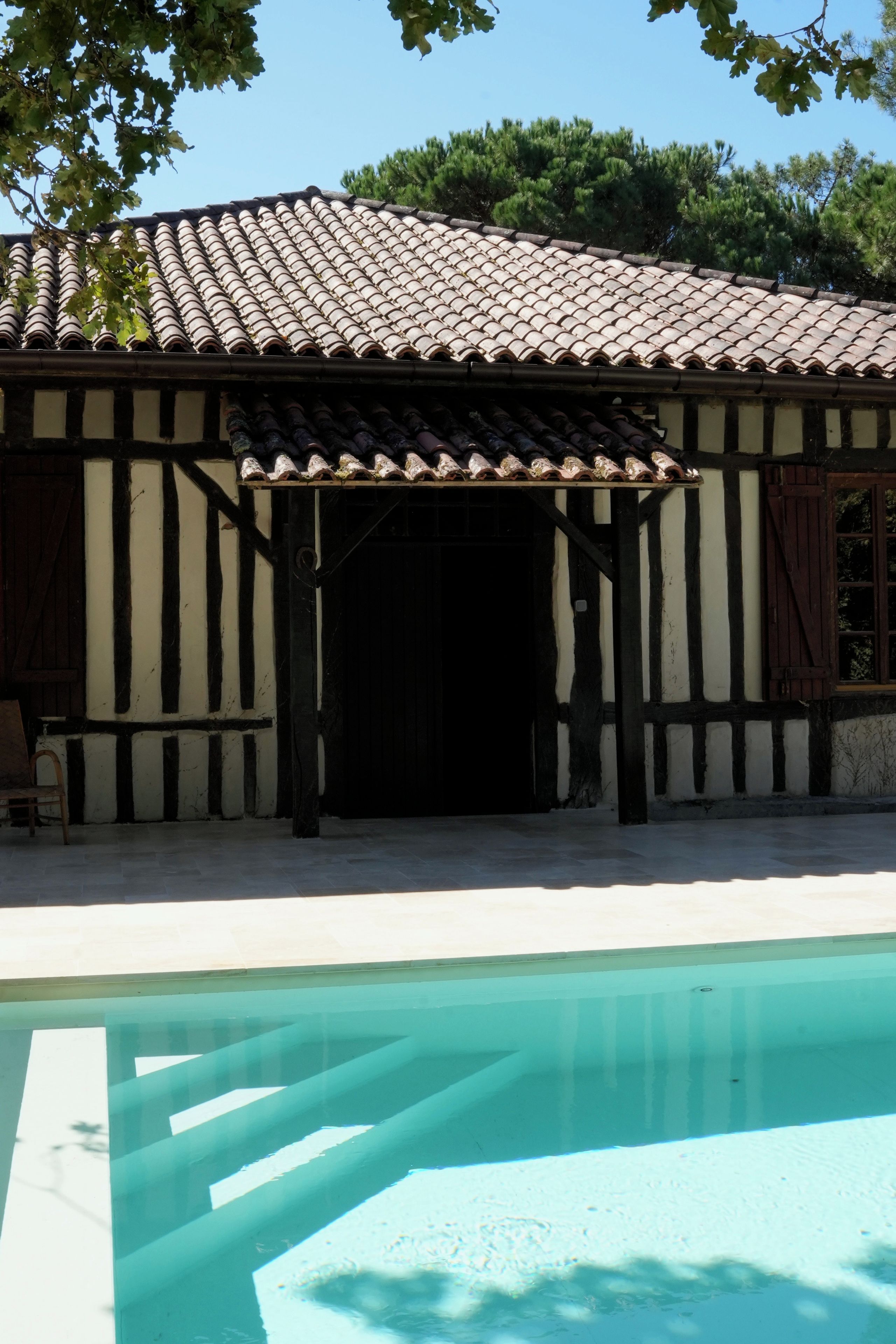 A building with a tiled roof and a pool in the foreground.