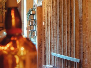 Ein Holzinterieur mit einem Metallregal an der Wand, einem weißen Stuhl und einer Flasche im Vordergrund.