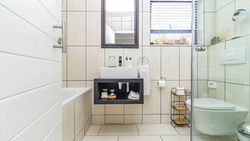 A modern bathroom with a white sink, mirror, and toilet.