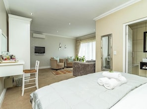 A hotel room with a bed, a desk, a chair, a television, a mirror, and a bathroom.