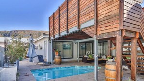A modern house with a pool, wooden deck, and outdoor seating area. - Hermanus Cliff Path Lodge (Hermanus)