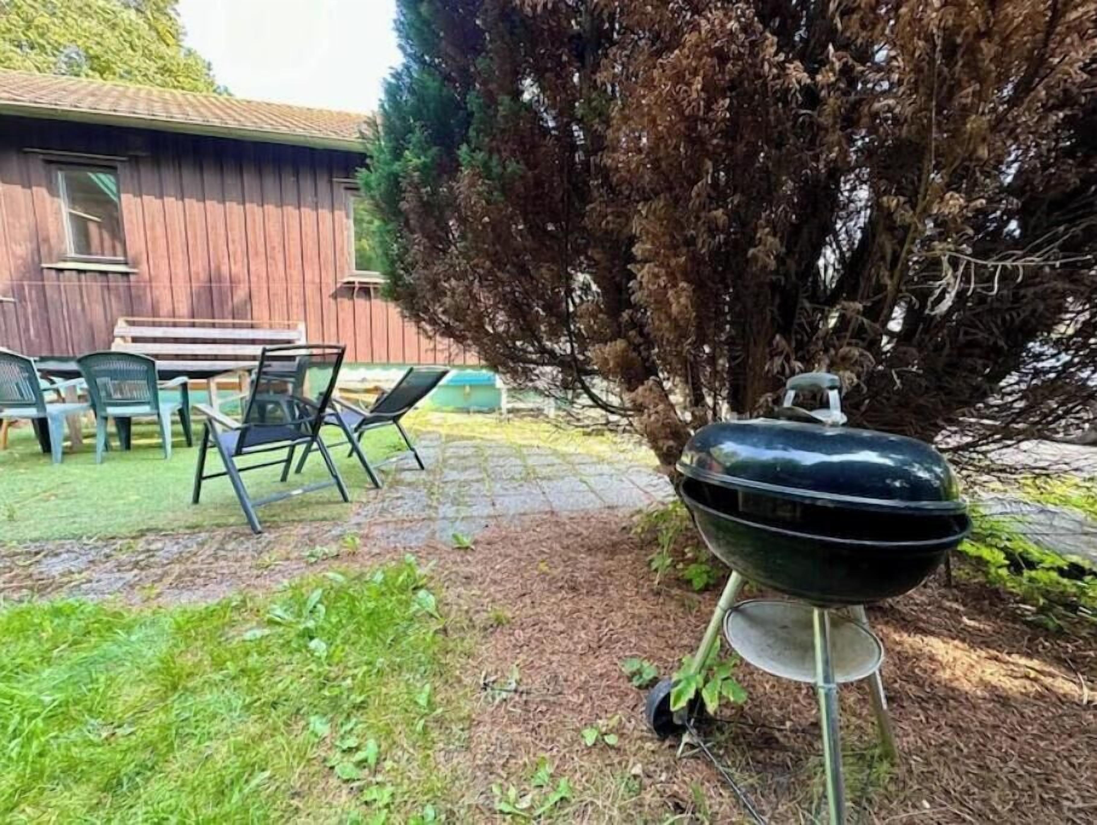 Een achtertuin met een barbecue, een houten schutting en een tafel met stoelen.