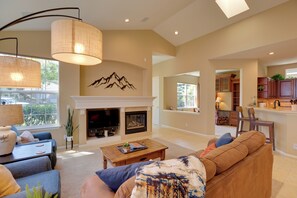 A spacious living room with a fireplace, a dining area, and a kitchen. - Bend Home: Office, Garage, Parks, Seasonal Pool! (Bend)