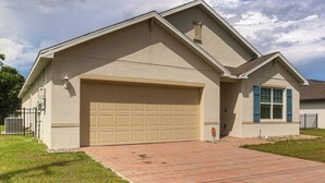 A residential house with a garage, a brick driveway, and a small lawn. - Lanai & Fenced Yard! Home 8 Mi to Charlotte Harbor (Punta Gorda)