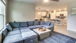 A modern living room with a sectional sofa, a coffee table, and a ceiling fan. - Lanai & Fenced Yard! Home 8 Mi to Charlotte Harbor (Punta Gorda)