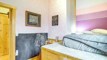 Een slaapkamer met een bed, een houten dressoir, een klein tafeltje en een muur met twee ingelijste foto's.