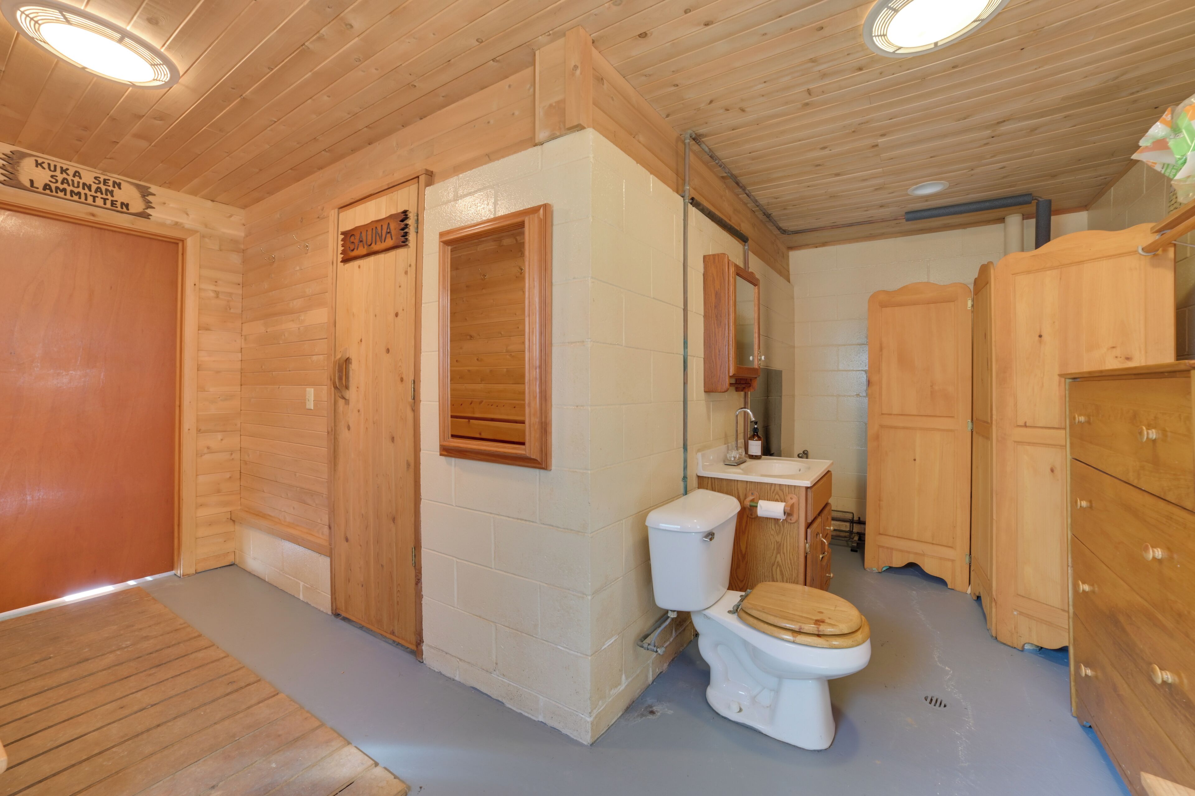 Un interior de madera con sauna, un inodoro y armarios de madera.