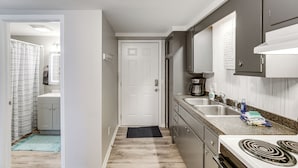A kitchen with a stove, sink, and cabinets.