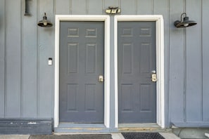 Two grey doors with white frames, a small window, and two wall-mounted light fixtures.