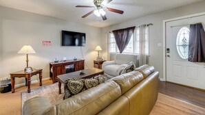 A living room with a sofa, coffee table, lamps, TV, and a ceiling fan. - Spacious Yard! Family Home, 10 Mi to Fort Bragg (Fayetteville)