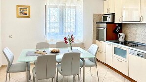 A dining area with a glass table, four chairs, a vase with flowers, and a painting on the wall. - Gorgeous home in Trilj (Trilj)