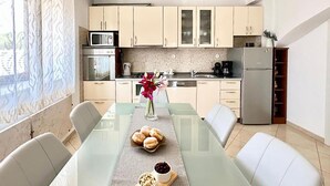 A modern kitchen with a dining table, chairs, and a vase of flowers. - Gorgeous home in Trilj (Trilj)