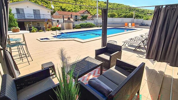 A poolside area with outdoor furniture, a swimming pool, and a view of houses in the background. - Gorgeous home in Trilj (Trilj)