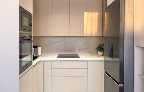 Eine moderne Küche mit Einbauofen, Edelstahlkühlschrank und Marmor-Spritzschutz.