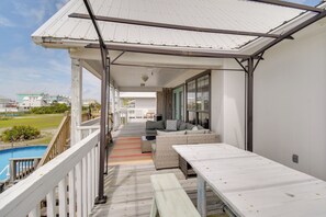 A covered outdoor deck with a pool, a sofa, and a table. - Unwind Poolside, Walk to Beach! Gulf Shores Escape (Gulf Shores)