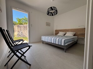 Ein Schlafzimmer mit Bett, Sessel, Pendelleuchte und Blick ins Freie.