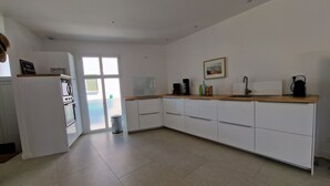 A modern kitchen with white cabinets, a wooden countertop, and a large window. - Escapade rochelaise: new, modern house (La Rochelle)