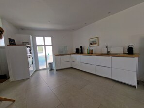 Eine moderne Küche mit weißen Schränken, einer Holz Arbeitsplatte und einem großen Fenster.
