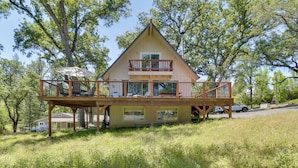 A two-story house with a balcony, surrounded by trees.