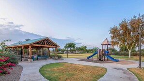 Ein Park mit einem Pavillon, einem Spielplatz und blauem Himmel.