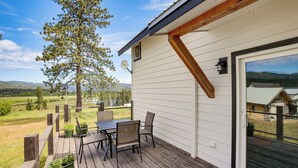 Une terrasse en bois avec une table et des chaises, une antenne parabolique et une vue sur un paysage montagneux.