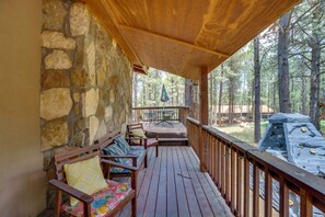 Eine Holzterrasse mit Steinmauern, ein überdachter Sitzbereich mit Kissen und ein Grill im Hintergrund.