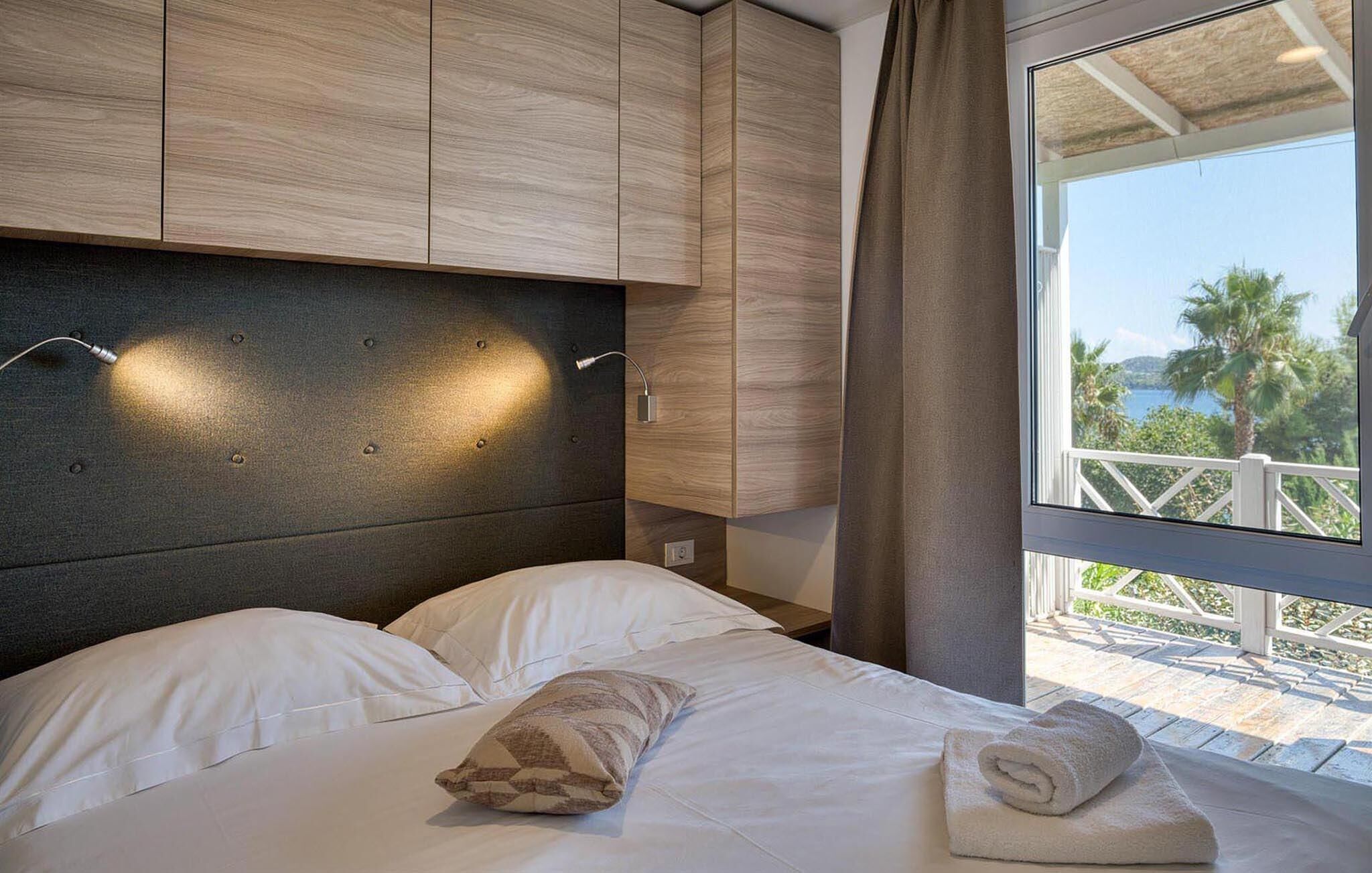Una camera da letto con un letto, una testiera, una finestra vista e una tenda.
