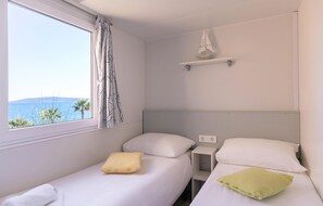 Ein kleines Zimmer mit einem Einzelbett, einem Fenster mit Blick auf eine schöne Aussicht, einem Nachttisch und einem Regal mit einem dekorativen Gegenstand.