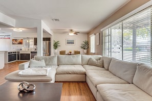Ein modernes Wohnzimmer mit einem Ecksofa, einem Couchtisch aus Holz und einem Deckenventilator.