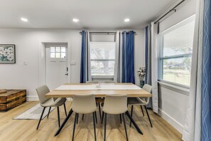 A dining area with a wooden table, four chairs, a vase with flowers, and a window with blinds. - Work & Play in Palmetto! Pet-Friendly Home w/ Yard (Palmetto)