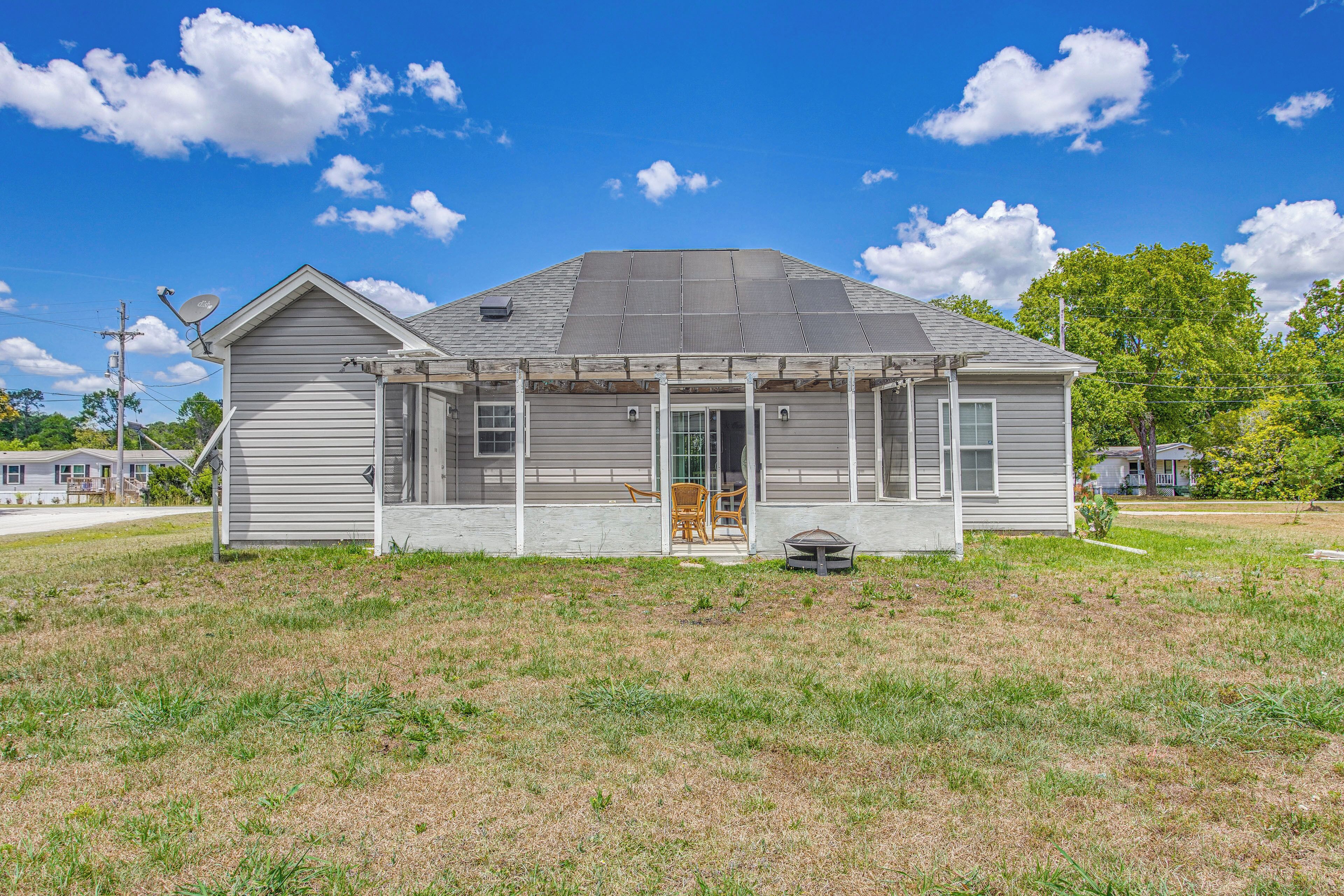 A single-story house with a covered porch, a satellite dish, and a small outdoor seating area.
