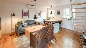 A cozy living area with a sofa, a dining table, wicker chairs, a floor lamp, and a staircase. - 2 bedroom lovely apartment in Kolind (Kolind)