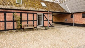 A traditional building with a cobblestone courtyard, a wooden bench, and a door. - 2 bedroom lovely apartment in Kolind (Kolind)