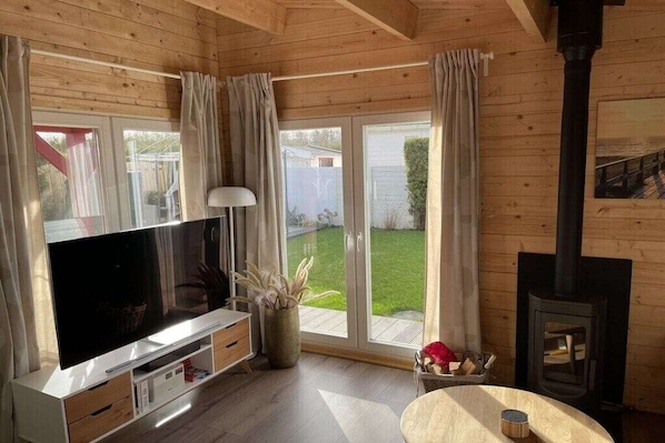 Ein gemütliches Zimmer mit Fernseher, Kamin und einer Glastür zum Garten.