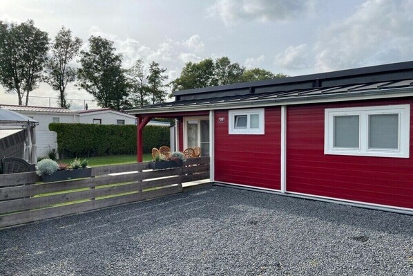 A red building with a gravel driveway and a wooden fence. - Holiday home in Menaldum with swimming pool (Menaldum)