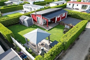 Ein Wohngebiet mit einem roten Haus, einer überdachten Terrasse und einem kleinen Schuppen.