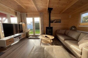 Ein Holzinnenraum mit einer Couch, einem Fernseher und einem Kamin.