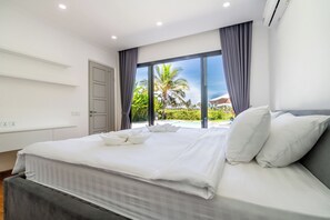 Una habitación de hotel moderna con una cama grande, vistas a palmeras y un balcón.