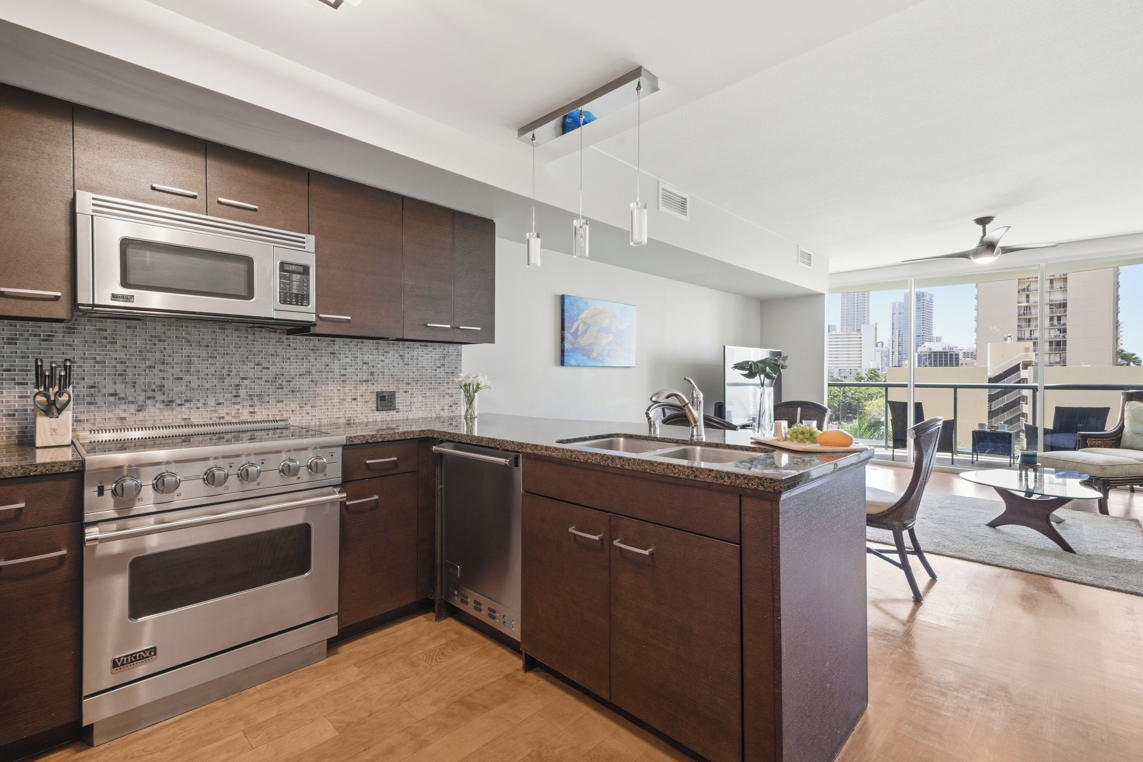 Cozinha moderna com eletrodomésticos de aço inoxidável, uma ilha grande com pia e vista para a cidade através de amplas janelas.