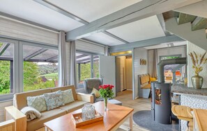 Ein modernes Interieur mit einer Couch, einem Tisch, einem Blumenstrauß und einem Kamin.