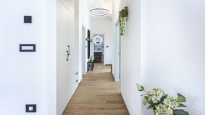 A modern hallway with a wooden floor, a circular mirror, and a hanging plant.