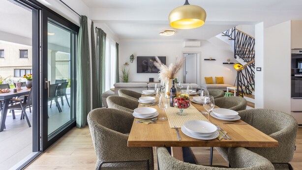 A dining area with a wooden table, chairs, and a hanging light fixture.