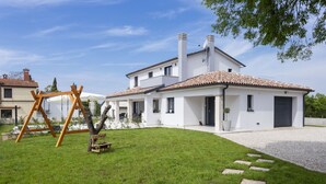 A modern house with a white exterior, a tiled roof, and a well-maintained lawn.