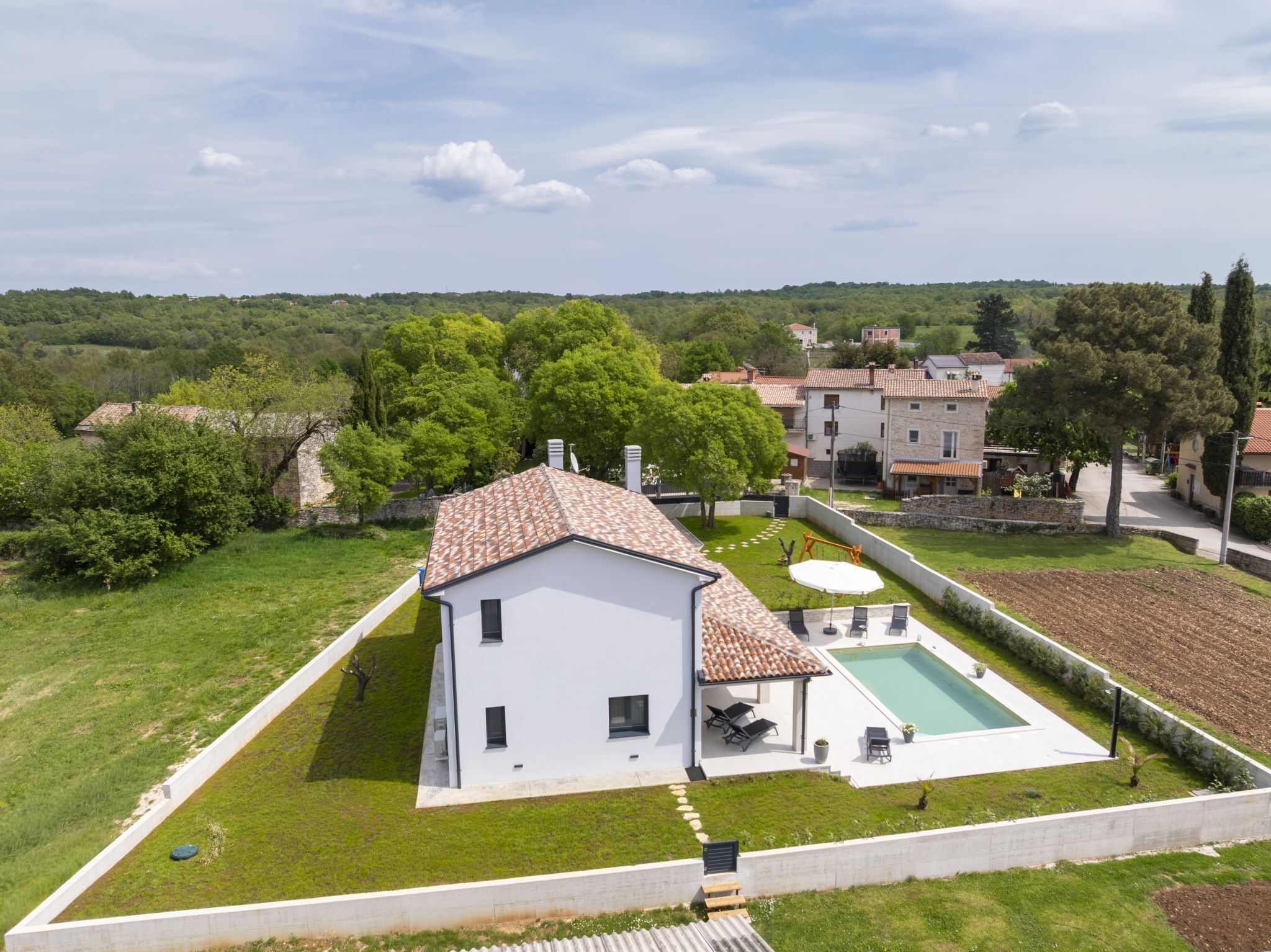A modern house with a swimming pool, surrounded by a well-maintained lawn and trees.