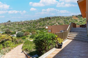 A balcony with a view of a hilly landscape, a potted plant, and a satellite dish.