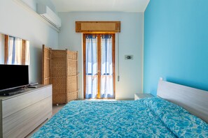 Ein Schlafzimmer mit einem Bett, einem Schminktisch, einem Fernseher und einem Korbwandschrank.