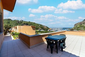 Eine Terrasse mit Tisch und Stühlen, Blick auf eine Marina und Gebäude im Hintergrund.