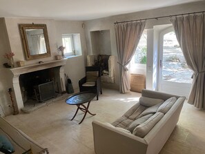 Ein Wohnzimmer mit einer Couch, einem Kamin, einem Spiegel und Blick durch eine Tür.