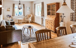 A cozy living room with a sofa, chairs, a dining table, a cabinet, and a chandelier. - 2 bedroom nice home in Hundested (Hundested)