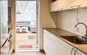 Una cocina compacta con un lavamanos, armarios y piso de madera.
